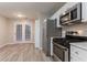 An airy kitchen showcasing stainless steel appliances, light gray flooring, and access to the backyard patio at 7113 Ambercrest Ct, Austell, GA 30168