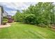 Large backyard featuring green grass, trees, and a stone patio at 6345 Sterling Shores Dr, Cumming, GA 30041