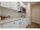 Stylish wet bar area displaying marble countertops, white cabinetry, and a stainless steel microwave at , Cumming, GA 30041