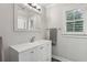 Bright bathroom with a white vanity, stylish mirror, shuttered window, and neutral wall color at 905 Brooksglen Dr, Roswell, GA 30075