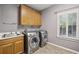 Functional laundry room with wooden cabinets, stainless steel washer and dryer, and bright natural light at 905 Brooksglen Dr, Roswell, GA 30075