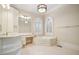 Bright bathroom features a large tub, vanity and arched windows with plantation shutters at 973 Peachtree Battle Ave, Atlanta, GA 30327