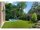 Green backyard with a modern pool, artificial turf, and a privacy fence with mature trees at 27 Maddox Ne Dr, Atlanta, GA 30309