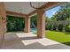 Covered patio with brick columns, tile floor, outdoor lighting, and a view of the lush backyard and pool at 27 Maddox Ne Dr, Atlanta, GA 30309