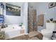 Bathroom featuring a soaking tub next to a toilet and a window with colorful curtains and natural light at 3470 Whisperwood Nw Ct, Marietta, GA 30064