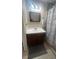 Well-lit bathroom showcasing a dark wood vanity, framed mirror, and a shower with patterned curtains at 585 Station View Run, Lawrenceville, GA 30043