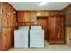 Functional laundry room features wood paneled walls and includes a washer, dryer, and cabinet at 2175 Fisher Ne Trl, Atlanta, GA 30345