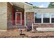 Close up of the brick front porch featuring a red door, white railings, and a bird bath at 2315 Tuxedo Se Dr, Marietta, GA 30067