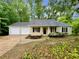 Inviting home featuring a two-car garage, neutral siding, black shutters, and a landscaped garden at 6026 Woodcreek Dr, Woodstock, GA 30188