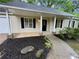 Close-up of the front porch area with stone accents, black door, and manicured landscaping at 6026 Woodcreek Dr, Woodstock, GA 30188