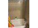 An outdated bathroom with tan tile and a colorful shower curtain at 1481 Pine St, Stone Mountain, GA 30087