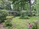 View of exterior of the home surrounded by green trees and bushes, with overgrown lawn at 1481 Pine St, Stone Mountain, GA 30087