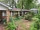 View of the home's side and front shows a red brick exterior and an overgrown front yard at 1481 Pine St, Stone Mountain, GA 30087