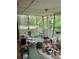 Enclosed back porch with green flooring, white railing and ceiling, and wooded backyard at 1481 Pine St, Stone Mountain, GA 30087