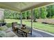 Covered patio with comfortable seating overlooks a lush, green backyard surrounded by trees at 13055 Fox Rd, Alpharetta, GA 30005