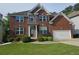 Charming two-story red brick home featuring a manicured lawn and a two car garage at 232 Clubhouse Xing, Acworth, GA 30101
