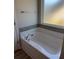 A crisp white bathtub features tiled backsplash and chrome hardware in this bright, modern bathroom at 457 Panhandle Pl, Hampton, GA 30228