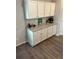 A view of the kitchen's stylish cabinetry and countertop with decorative items and wood look floors at 457 Panhandle Pl, Hampton, GA 30228