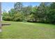 Spacious backyard featuring a lush lawn area, mature trees, and a recreational trampoline at 237 River Pass Ct, Dacula, GA 30019