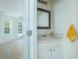 Half bath featuring a pedestal sink, framed mirror, and adjacent sunroom with natural light at 237 River Pass Ct, Dacula, GA 30019