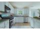 Bright kitchen features white cabinets, stainless steel appliances, and a window over the sink at 237 River Pass Ct, Dacula, GA 30019