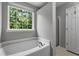 Relaxing soaking tub with a window view in a neutral toned bathroom at 411 Sugar Maple Ct, Canton, GA 30114