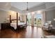 Spacious main bedroom with a tray ceiling, hardwood floors, and french doors leading to a balcony at 1409 Spyglass Hill Dr, Johns Creek, GA 30097