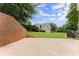 Landscaped backyard with a retaining wall, concrete patio, and lush lawn leading up to the house at 3040 Larkspur Ct, Cumming, GA 30041