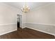 Dining room featuring wood floors, elegant chandelier, and wainscoting, with a doorway view of a stainless steel refrigerator at 3040 Larkspur Ct, Cumming, GA 30041