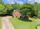 View of the brick home on a large lot featuring an expansive lawn with beautiful, mature trees and a circular driveway at 3040 Larkspur Ct, Cumming, GA 30041