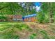 Exterior shot of a brick home with blue tarp, showing its setting on a spacious lot with lush trees at 2180 Rexford Dr, Decatur, GA 30034