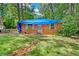 View of a brick home with a blue tarp covering the roof and an overgrown front yard at 2180 Rexford Dr, Decatur, GA 30034