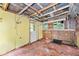 Sunroom with peeling yellow paint, damaged flooring, and multiple windows at 2180 Rexford Dr, Decatur, GA 30034