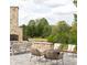 Outdoor patio featuring stone fireplace, ample seating, and a view of the surrounding landscape at 4815 Ramblewood Dr, Cumming, GA 30028
