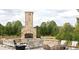 Outdoor patio with stone fireplace, seating area, and views of the lush greenery at 4815 Ramblewood Dr, Cumming, GA 30028