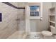 Bathroom featuring a shower with marble and blue tiling, plus vanity storage and a window for natural light at 1100 Welch Sw St, Atlanta, GA 30310