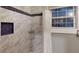 Bathroom showcasing a shower with sleek marble tiling, a niche, and dark blue accents, paired with a bright window at 1100 Welch Sw St, Atlanta, GA 30310