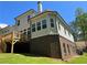 Rear view of a house featuring a wooden deck overlooking a spacious backyard with a brick facade at 3730 Reserve Overlook (Lot 8) Way, Cumming, GA 30041
