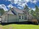 Rear view of a house featuring a dark roof, siding, and a wooden deck overlooking a spacious backyard at 3730 Reserve Overlook (Lot 8) Way, Cumming, GA 30041