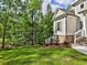 Lush backyard and home exterior, offering a view of its well-maintained lawn, stone accents, and private setting at 3730 Reserve Overlook (Lot 8) Way, Cumming, GA 30041