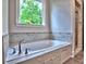 Bathroom with a soaking tub, marble tile surround, and a window overlooking the tree line at 3730 Reserve Overlook (Lot 8) Way, Cumming, GA 30041