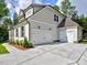 View of the three car garage with white doors, a concrete driveway, and partial side view of the home at 3730 Reserve Overlook (Lot 8) Way, Cumming, GA 30041