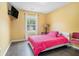 Comfortable bedroom with bright yellow walls, wood floors, and a mounted TV at 734 Kilkenny Cir, Lithonia, GA 30058