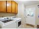 Well-equipped laundry room with wooden cabinets, washer, dryer, and access to the outside at 836 Palmetto Tyrone Rd, Sharpsburg, GA 30277