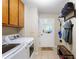 Bright laundry room featuring tile floors, wooden cabinets, washer, dryer, and hanging storage racks at 836 Palmetto Tyrone Rd, Sharpsburg, GA 30277