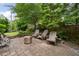 Charming stone patio with wood chairs and a modern fire pit, surrounded by lush greenery and a wooden fence at 1849 Rock Springs Ne Ln, Atlanta, GA 30324