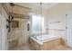 Luxurious bathroom featuring glass shower, separate soaking tub, and neutral stone tile at 2455 Ivey Oaks Rd, Cumming, GA 30041