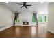 Bright living room with hardwood floors, fireplace, large windows with backyard views, and a ceiling fan at 2455 Ivey Oaks Rd, Cumming, GA 30041