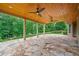 Wide shot of a stone patio with a wooden ceiling, dual fans, and wooded backyard views at 2455 Ivey Oaks Rd, Cumming, GA 30041
