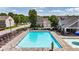 The community pool has lounge chairs, tables, umbrellas, and landscaping and a building adjacent to the pool at 556 Poplar Bnd, Canton, GA 30114
